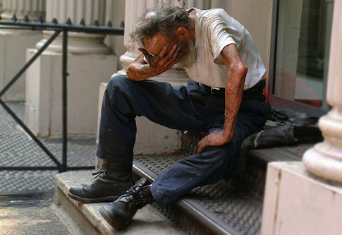 Пожилой неопрятный мужчина сидит на ступеньках возле дома и плачет | © Unsplash