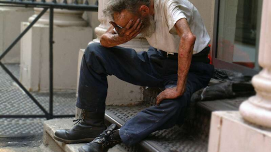 Пожилой неопрятный мужчина сидит на ступеньках возле дома и плачет | © Unsplash