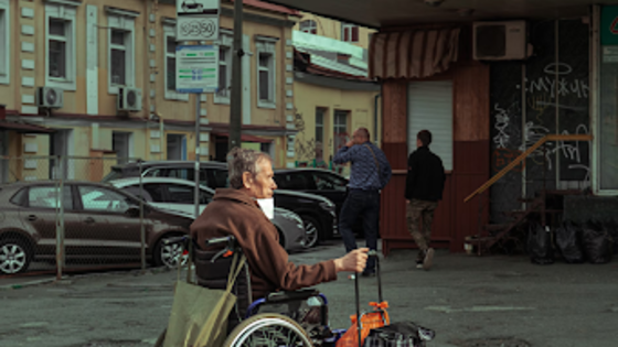 Старий на інвалідному візку з багажем шукає притулку під час війни. | © Unsplash