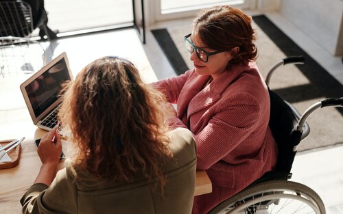 Жінка в інвалідному візку спілкується з дівчиною з ноутбуком | © Pexels